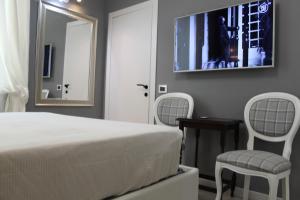 a bedroom with a bed and two chairs and a mirror at Jacuzzi apartament by parmacentro b&b in Parma