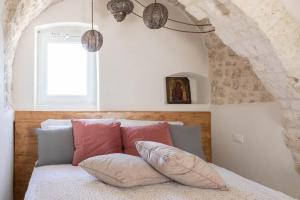 a bedroom with a bed with pillows and a window at Caterina's Suites & Apartament in Ostuni