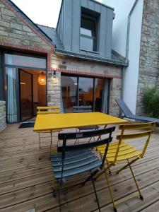 Les Villas de Locmiquel BORD DE MER في بادن: طاولة صفراء وكراسي على سطح خشبي