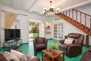 a living room with leather furniture and a staircase at Villa Magnolia in Cavtat