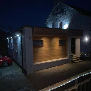 a house with a wooden garage door at night at The Juniperlea Inn in Pathhead