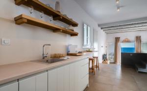 a kitchen with white cabinets and a sink and the ocean at Maison Esperia in Pollonia