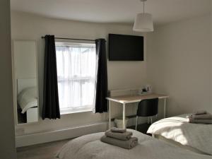 a bedroom with two beds and a desk and a window at The Swan Inn in Southampton