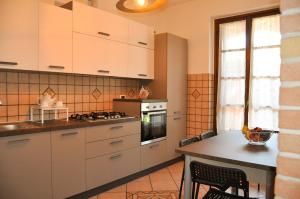 a kitchen with white cabinets and a table at Monolocale - B&B Sarita's Rooms in Certosa di Pavia