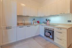 een keuken met witte kasten, een spoelbak en een vaatwasser bij CASA CAROLINA Mare, Comfort e Relax in Camogli