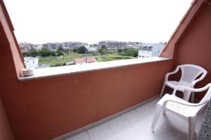 balcón con 2 sillas y vistas a la ciudad en Hostal San Roque, en Portonovo
