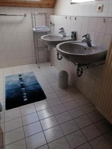 une salle de bain avec deux lavabos et un tapis bleu au sol dans l'établissement Ferienwohnung zum Wohlfühlen, à Altensteig