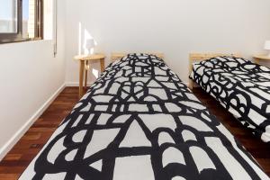 deux lits dans une chambre avec une couette noire et blanche dans l'établissement Guest H4U - Povoa Vacation, à Póvoa de Varzim