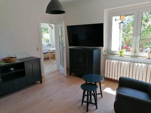 sala de estar con TV, sofá y taburete en Ferienhaus am Rand von Berlin - keine Monteursunterkunft, en Schönefeld