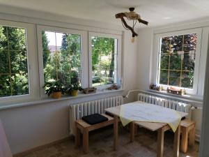 une salle à manger avec des fenêtres, une table et des bancs dans l'établissement Ferienhaus am Rand von Berlin - keine Monteursunterkunft, à Schönefeld