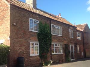 a red brick house with white windows and ivy at The Old Posthouse B&B in Caenby