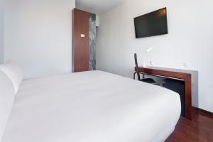 Schlafzimmer mit einem weißen Bett und einem TV in der Unterkunft B&B HOTEL e Apartamentos Felgueiras in Felgueiras