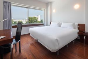 ein großes weißes Bett in einem Zimmer mit Fenster in der Unterkunft B&B HOTEL e Apartamentos Felgueiras in Felgueiras