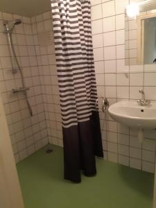 een badkamer met een zwart-wit douchegordijn en een wastafel bij Tiny house Veluwse Garre in Garderen