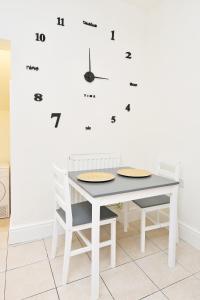 a white dining room table with chairs and a clock on the wall at Townhouse @ Earle Street Crewe in Crewe