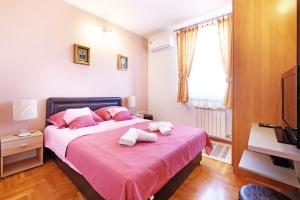 a bedroom with a pink bed with two towels on it at Villa Tower Gardos in Belgrade