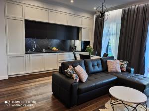 a living room with a black couch and a kitchen at Stara Wartownia in Zamość