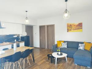 a living room and kitchen with a blue couch and a table at Meteora Rocks Apartment 1 in Kalabaka