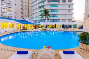 a large swimming pool with chairs and a building at Hotel Dann Cartagena in Cartagena de Indias