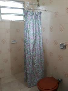 y baño con cortina de ducha y aseo. en Samburá Chalés, en Ilha Comprida