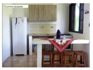 y cocina con mesa, sillas y nevera. en Samburá Chalés, en Ilha Comprida