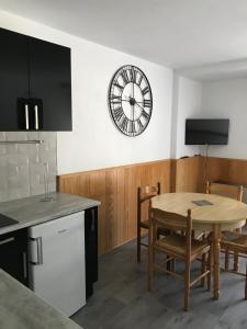 a kitchen with a table and a clock on the wall at Appartement au pied des pistes in Le Lioran