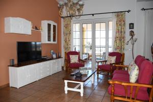 sala de estar con TV de pantalla plana y sillas rojas en Pedro's house with fantastic views, en Telde