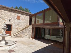 an external view of a stone house with glass doors at Villageermis - Casa Rural in Moraña