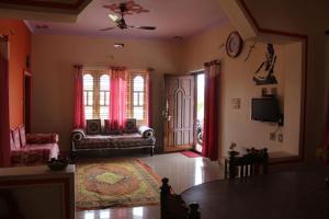 uma sala de estar com uma mesa, um sofá e janelas em Comfort Zone Homestay em Madikeri