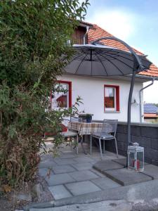 een patio met een tafel en een parasol bij Kim`s Cottage in Görwihl