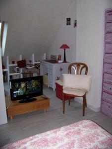 a living room with a television and a table with a chair at grande chambre lumineuse et spacieuse 22m2 in Guérande
