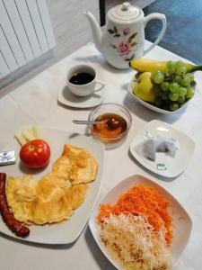 einen Tisch mit Teller mit Lebensmitteln und Obst in der Unterkunft Agropensiunea Ozon in Piatra Neamţ
