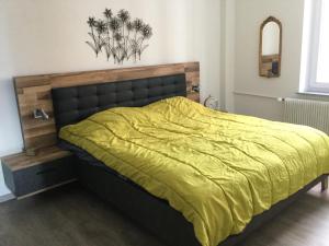 ein Schlafzimmer mit einem großen Bett und einer gelben Decke in der Unterkunft Appartement Wissembourg hyper centre in Wissembourg