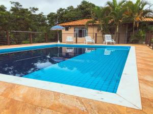a swimming pool with blue water in front of a house at Chalés JL in Capitólio
