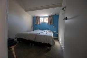 Schlafzimmer mit einem Bett mit blauer Wand in der Unterkunft BeachWay in Nes