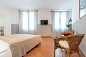 Cette chambre blanche dispose d'une table et d'une chaise. dans l'établissement Marinali Rooms, à Bassano del Grappa