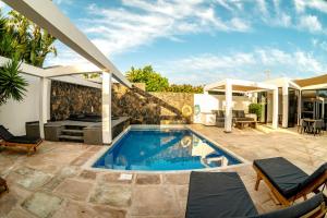 a swimming pool with a patio and a house at Casa Chani with heated pool in El Roque in Cotillo