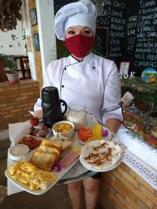 a person wearing a mask holding a tray of food at Pousada America do Sol in Natal