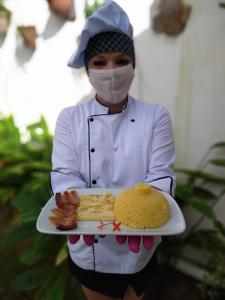une personne portant un masque portant une plaque de nourriture dans l'établissement Pousada America do Sol, à Natal