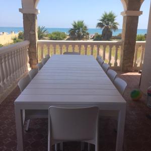 uma mesa e cadeiras numa varanda com praia em Beach House Villa Roca em Cullera