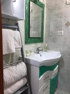 y baño con lavabo, espejo y toallas. en Cottage Azzurra, en Ischitella