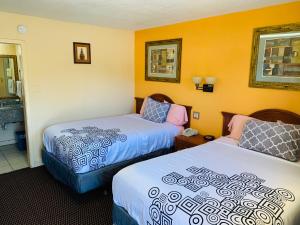 a hotel room with two beds and a bathroom at Budget Inn Jonesboro in Jonesboro
