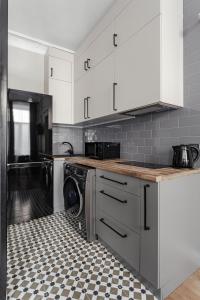 a kitchen with white cabinets and a black and white floor at City Centre Silver Apartment in Odesa