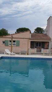 uma casa com piscina em frente a uma casa em Maisonnette au pied de la garrigue em Bernis