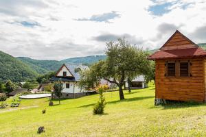 eine Holzhütte auf einem Feld mit einem Haus in der Unterkunft Chata VČELÁRIK in Nová Baňa