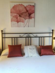 uma cama com almofadas vermelhas e um quadro por cima em La Casa Del Borgo em Beverino