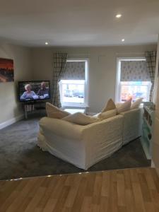 uma sala de estar com um sofá branco e uma televisão em Flat 2, 22 the square centre of Dalston village em Dalston