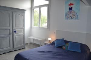 a bedroom with a blue bed and a window at LE POINT DU JOUR in Bon-Encontre