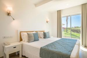 a bedroom with a large bed and a large window at Clube Porto Mos - Sunplace Hotels & Beach Resort in Lagos