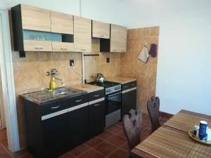 una cucina con armadi neri, lavandino e tavolo di Sétány Apartmanház Fonyód a Fonyód